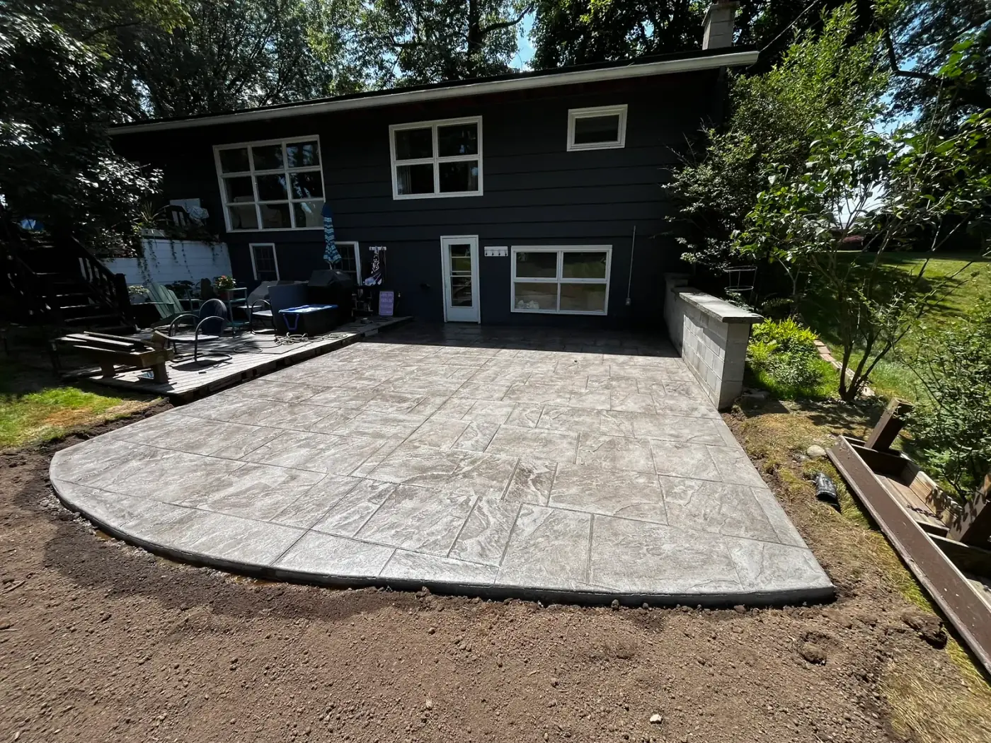 Finished 20 by 22 foot light gray stamped concrete patio with a curved edge