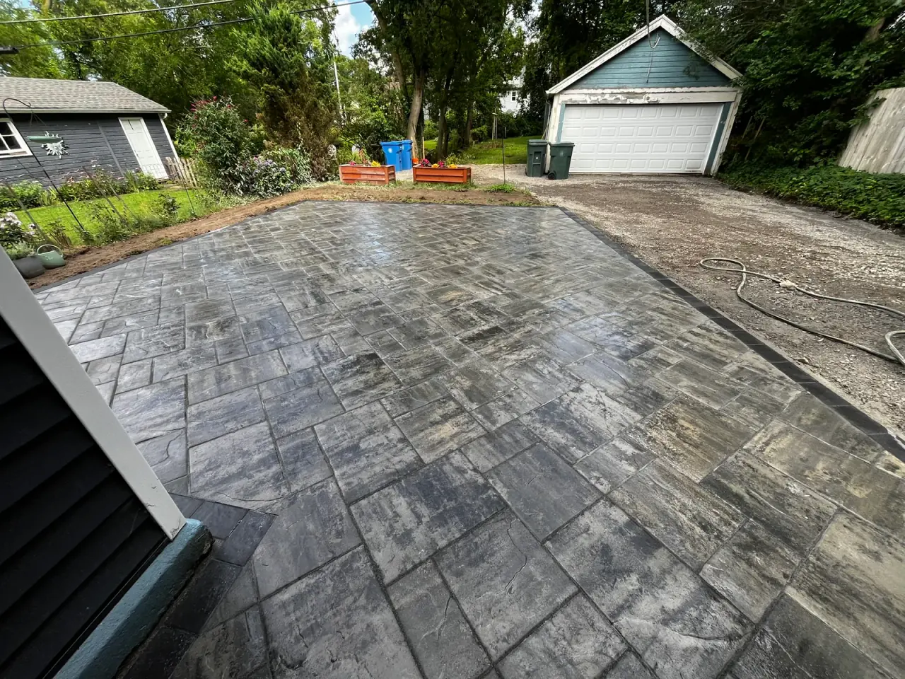 Large gray modular paver patio framed with a dark border